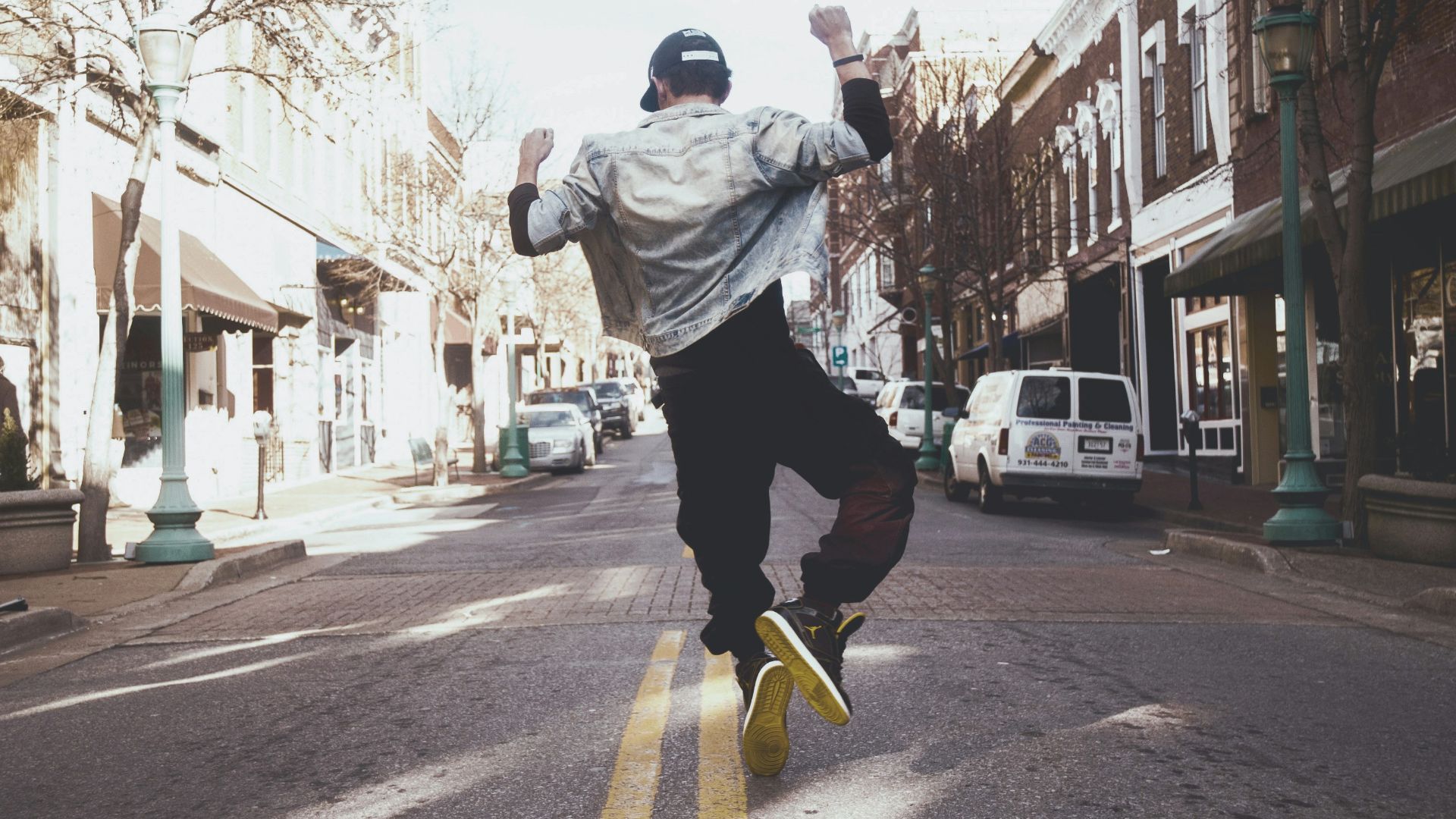 man jumping on the middle of the street during daytime