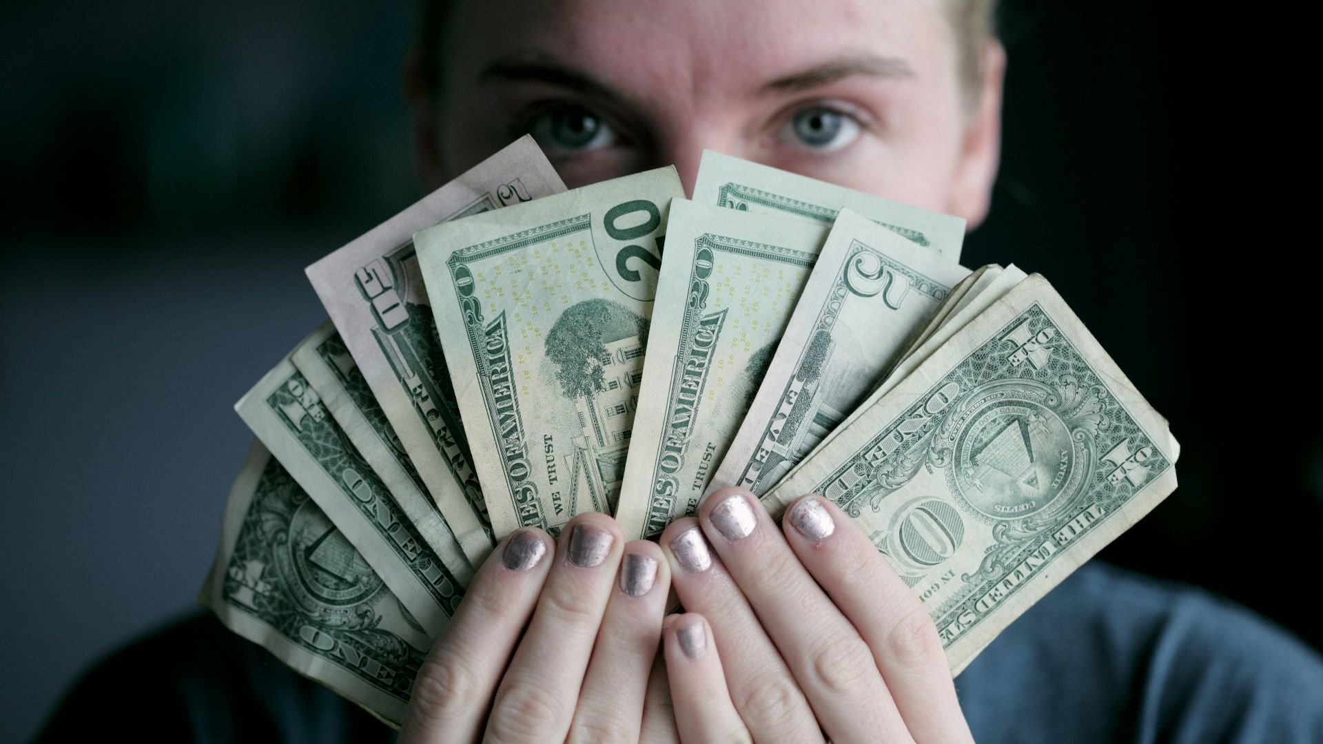 person holding fan of U.S. dollars banknote