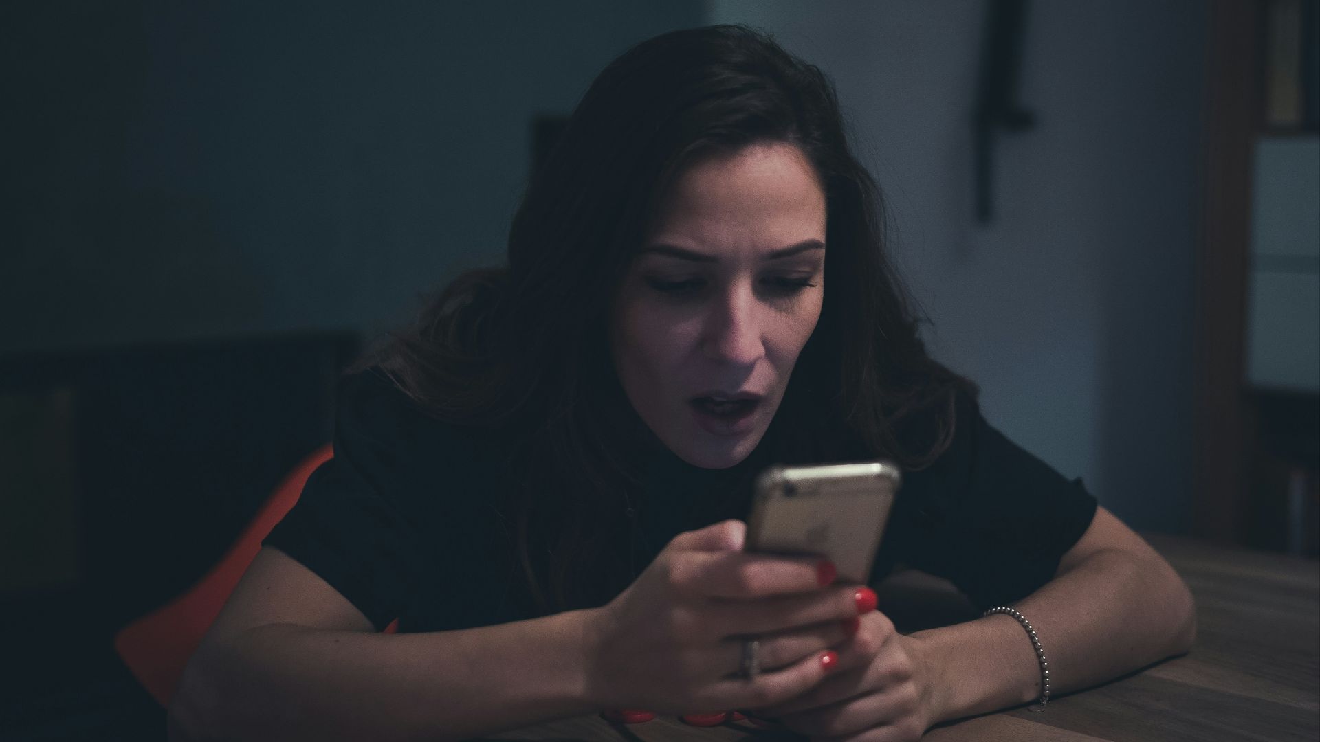 a person sitting at a table and looking at a phone