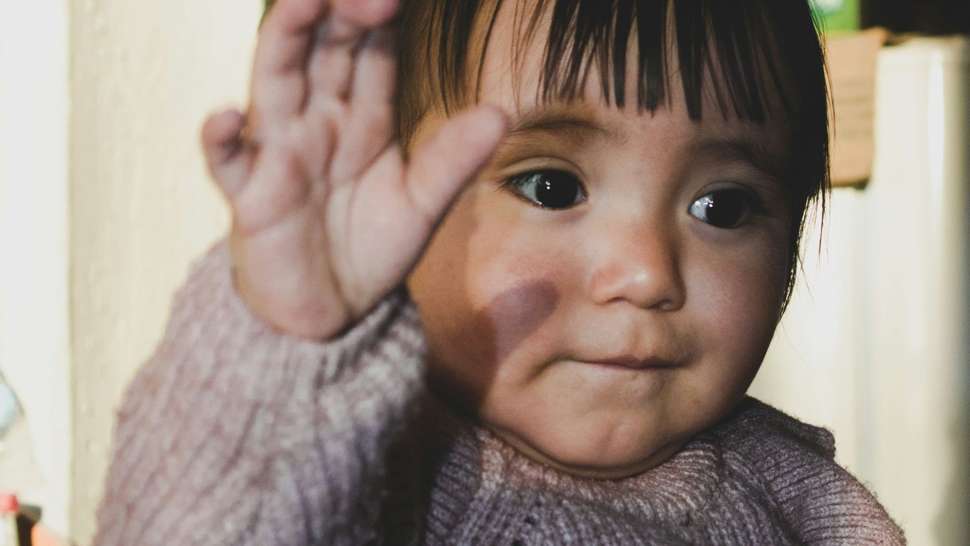 A young child holding his hand up to the camera
