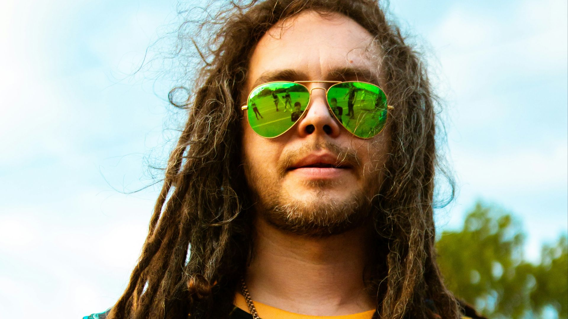 woman in blue yellow and red floral shirt wearing green sunglasses