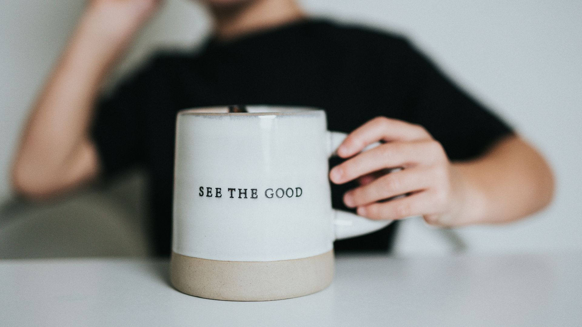 woman in black shirt holding white ceramic mug