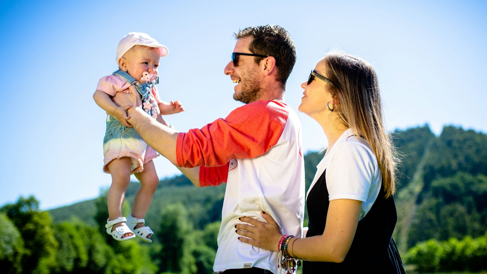 man in white and red polo shirt carrying girl in blue denim jeans during daytime