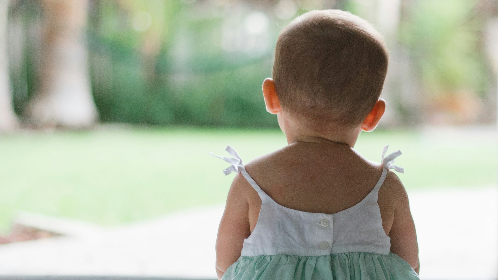 selective focus photo of toddler wearing sleeveless dress sitting on floor
