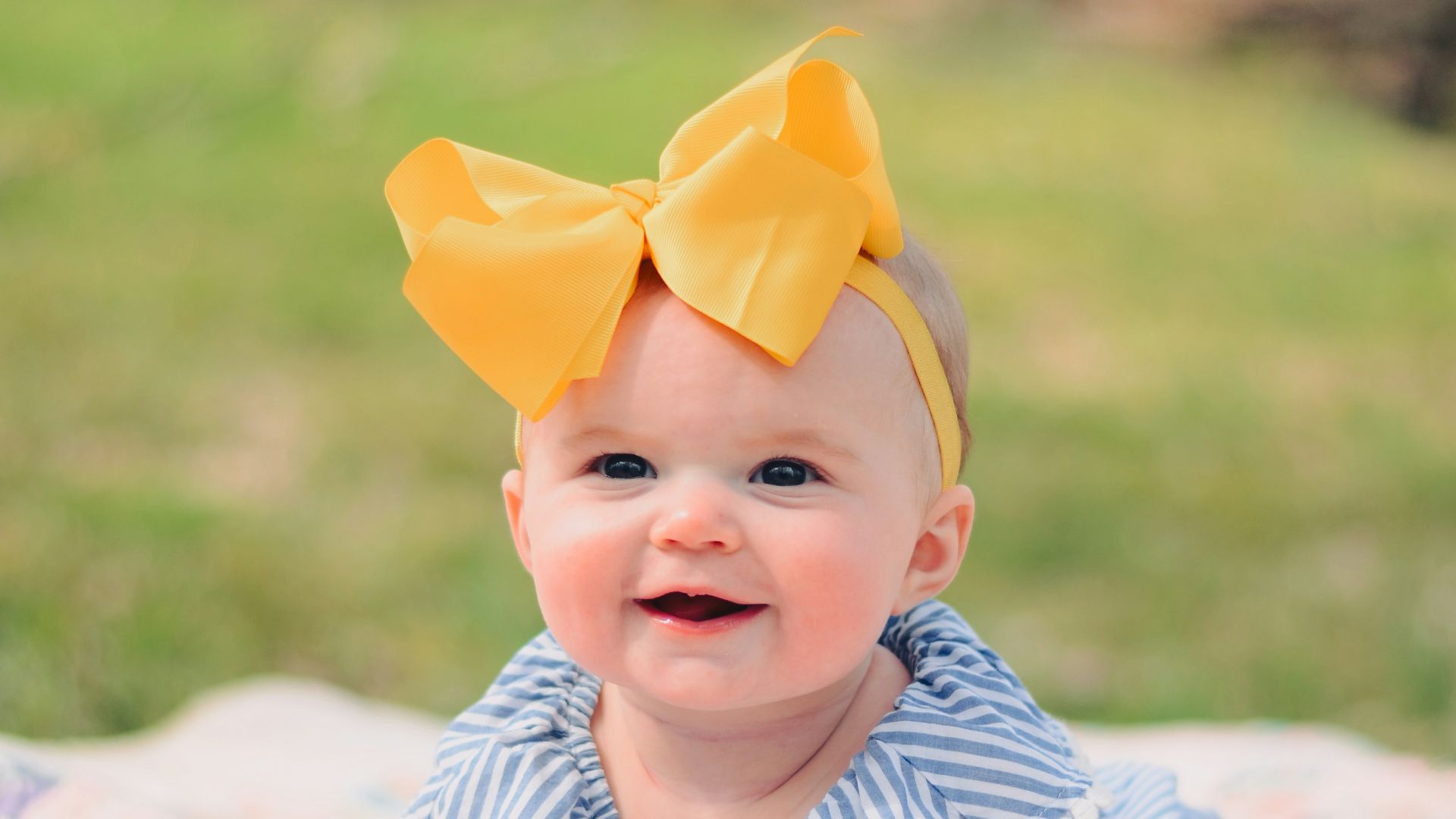 smiling baby lying forward on pink textile