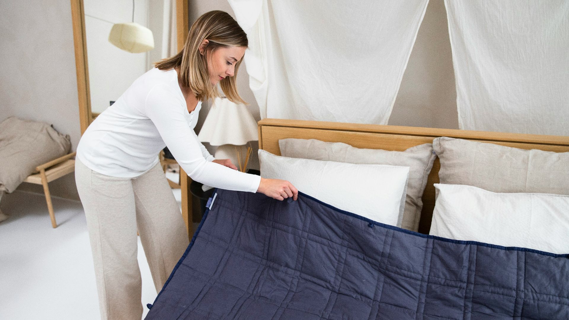 a woman putting a blue blanket on top of a bed