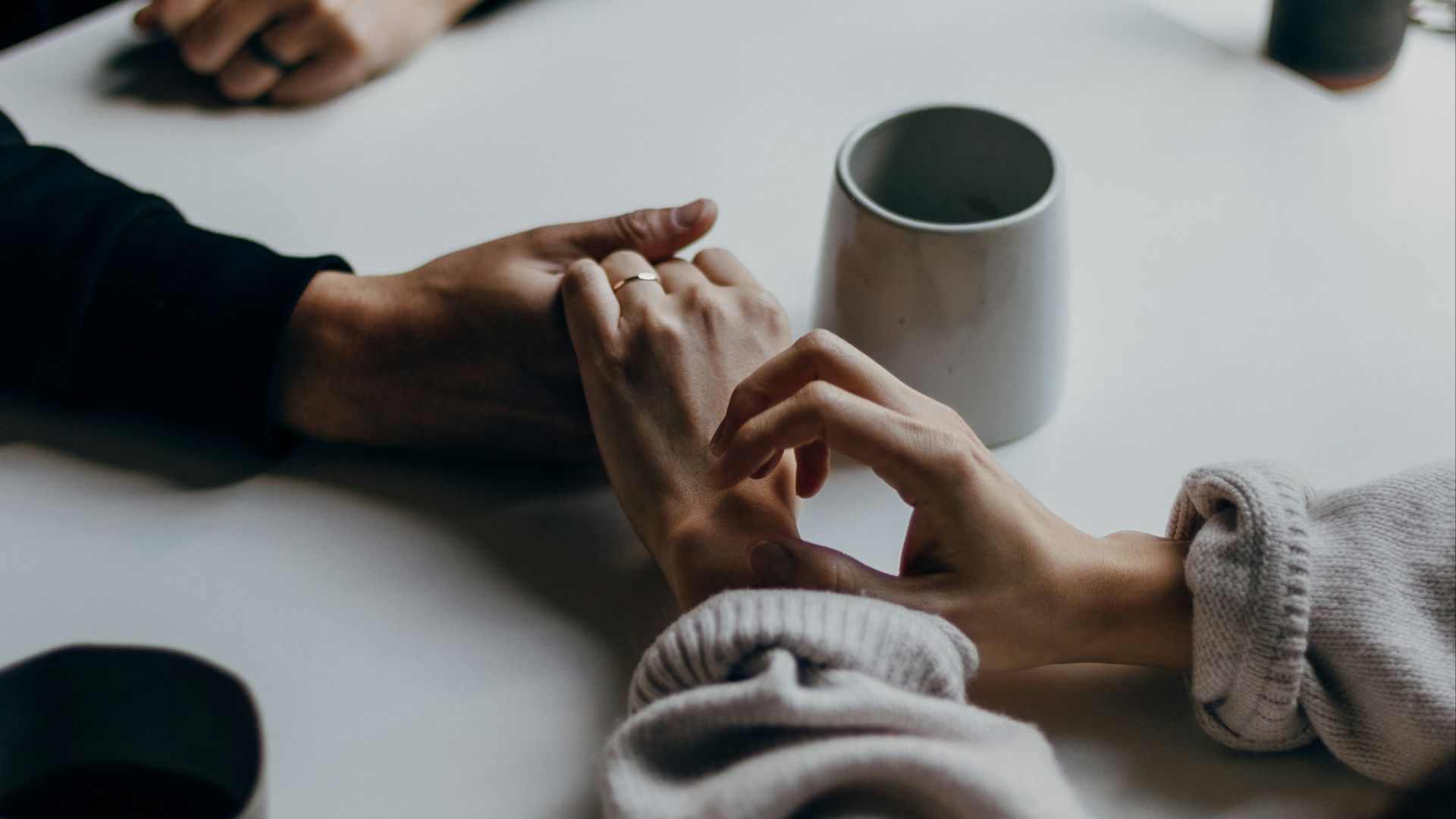 person in black long sleeve shirt holding white ceramic mug