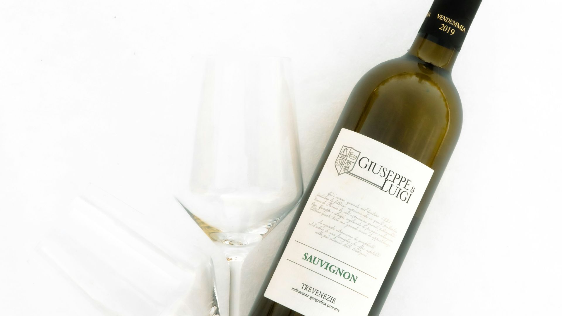 white labeled bottle beside clear wine glass