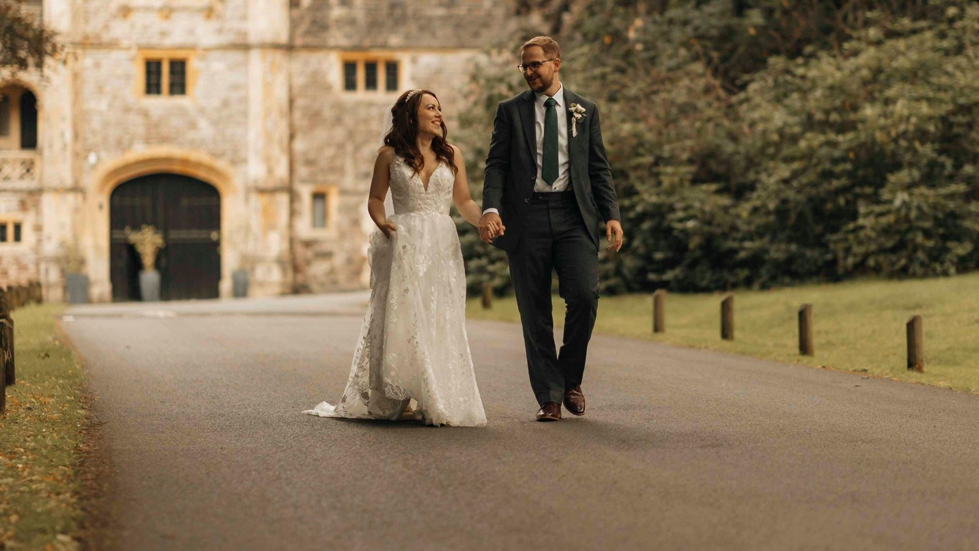 A bride and groom walking down a road in front of a castle