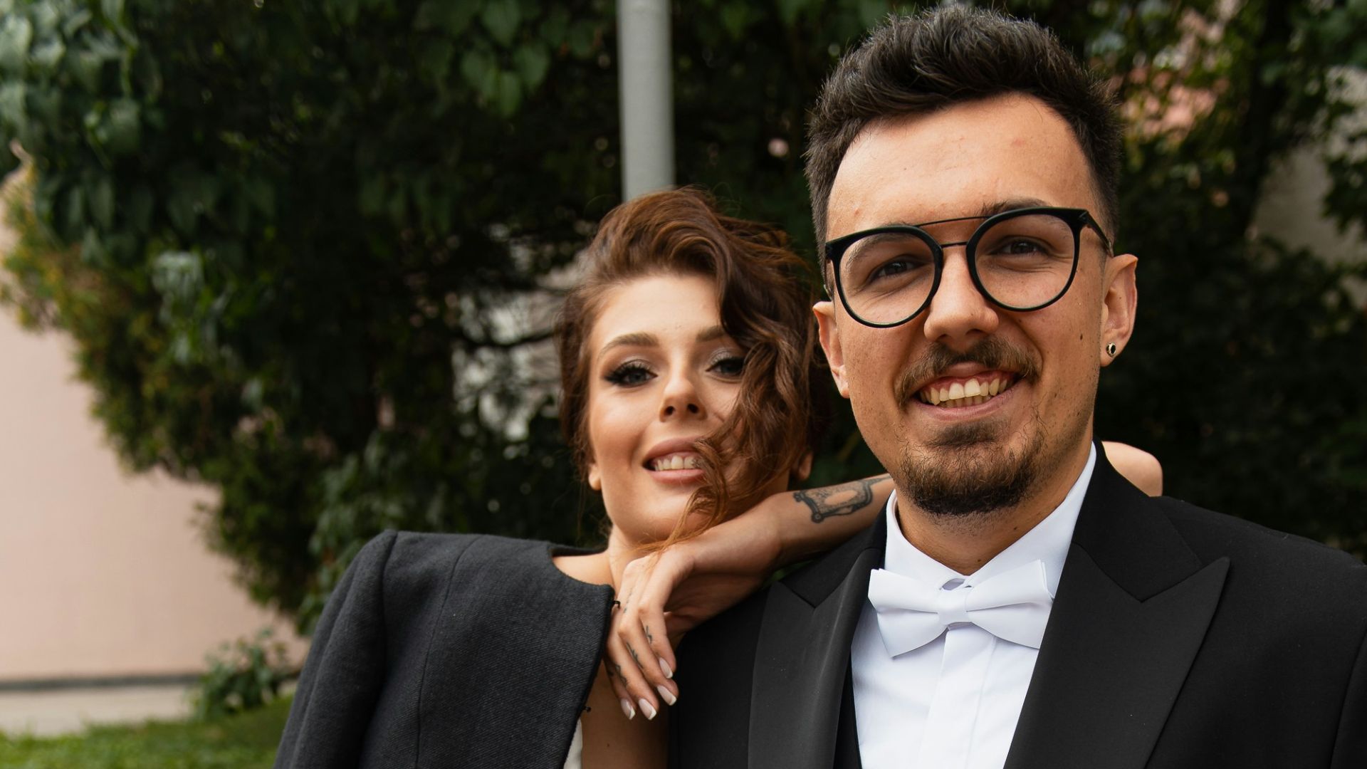 a man in a tuxedo and a woman in a white dress pose for