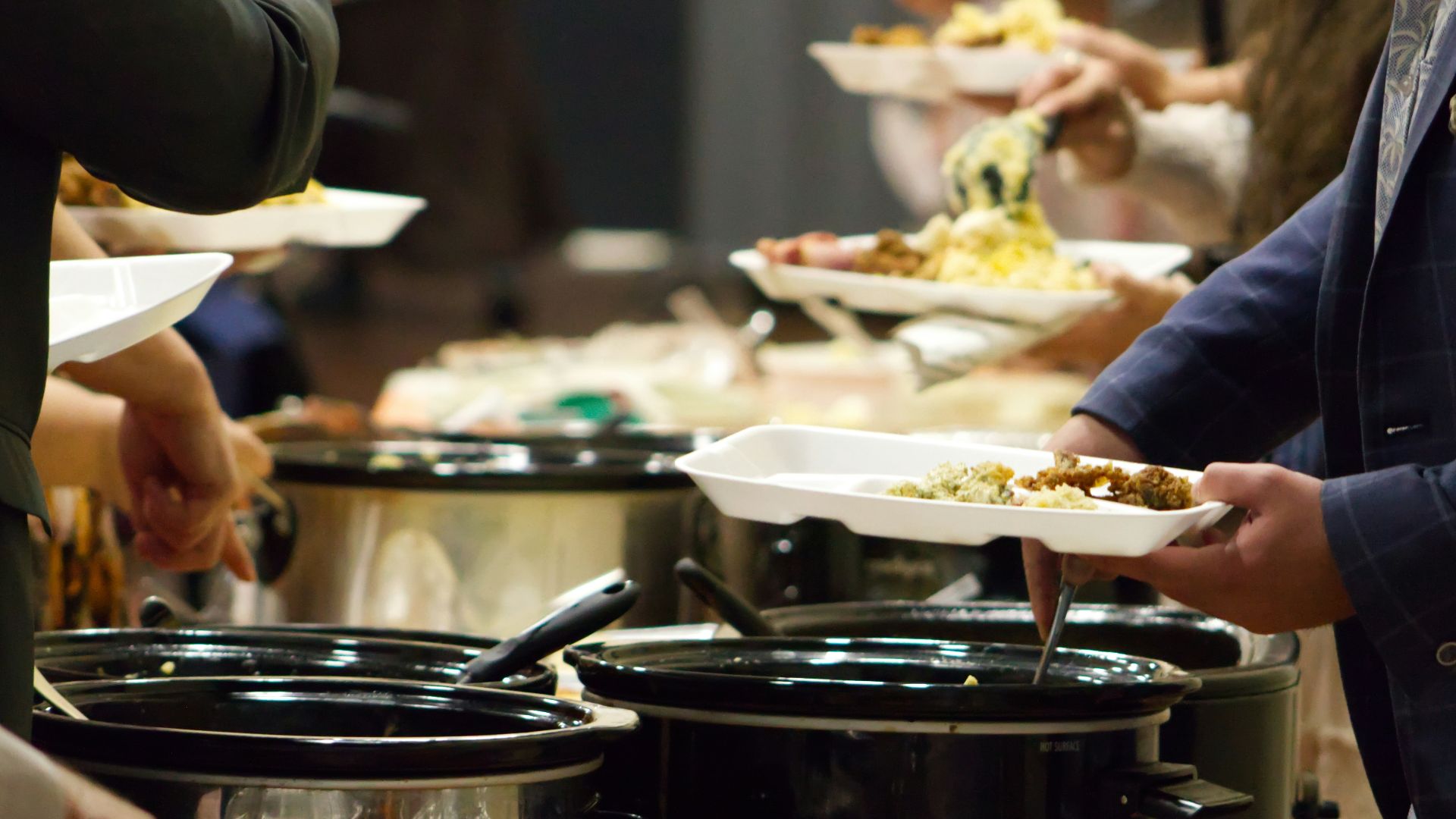 A group of people standing around a buffet line