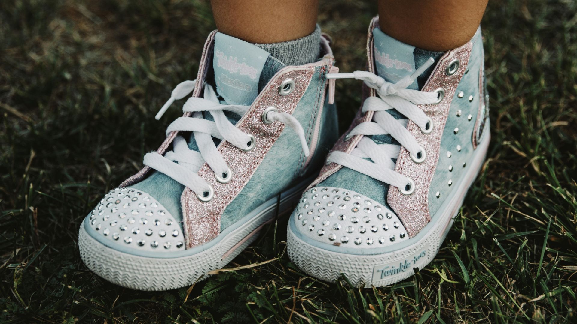 person wearing white and gray sneakers standing on green grass during daytime