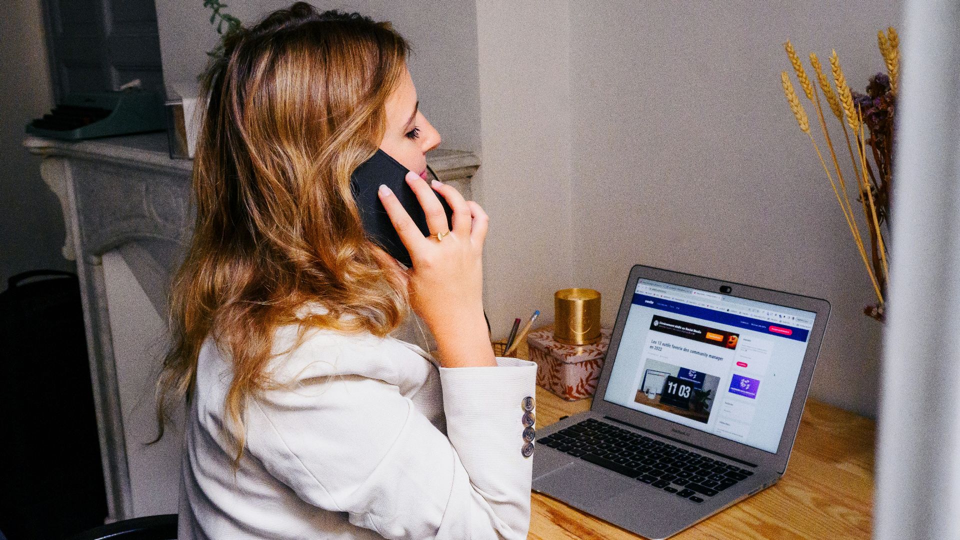 a woman sitting at a desk with a laptop and a phone