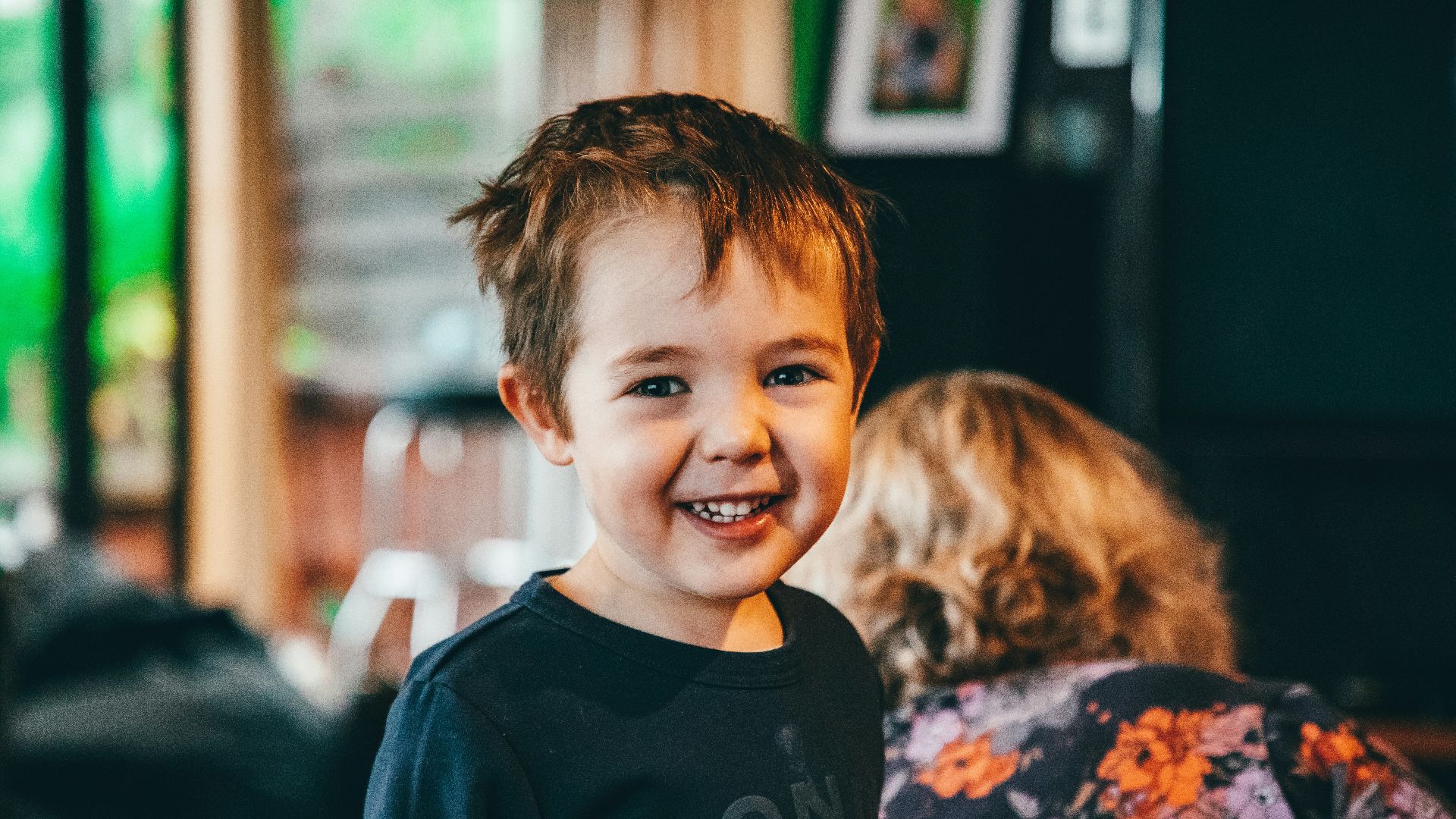 a young boy smiling at the camera in a restaurant