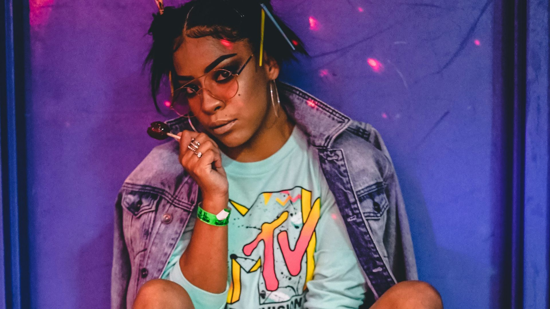 woman sitting wearing roller skates and jacket while holding lollipop