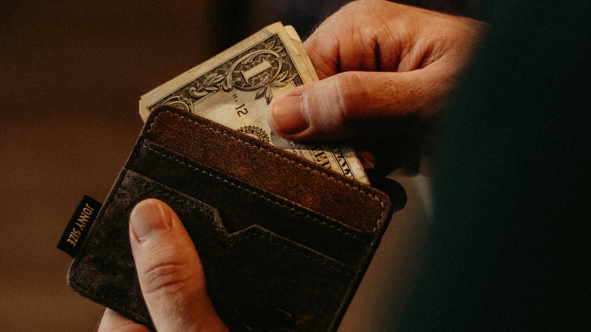 person getting 1 U.S. dollar banknote in wallet
