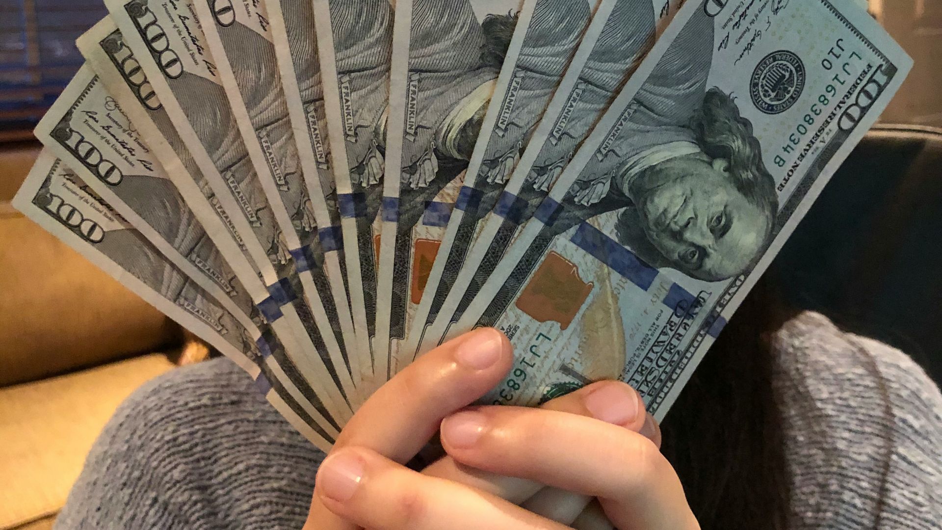 person holding fan of us dollar bill