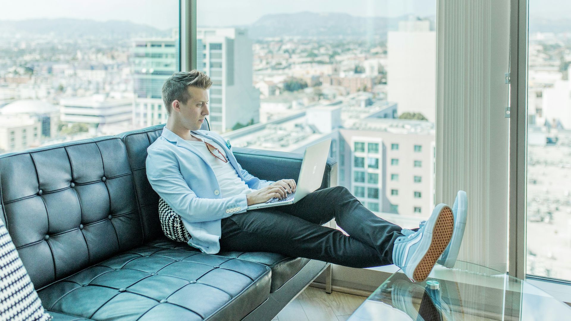 man sitting on sofa while using laptop