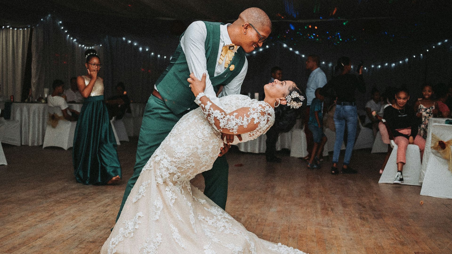 man in black suit jacket holding woman in white wedding dress