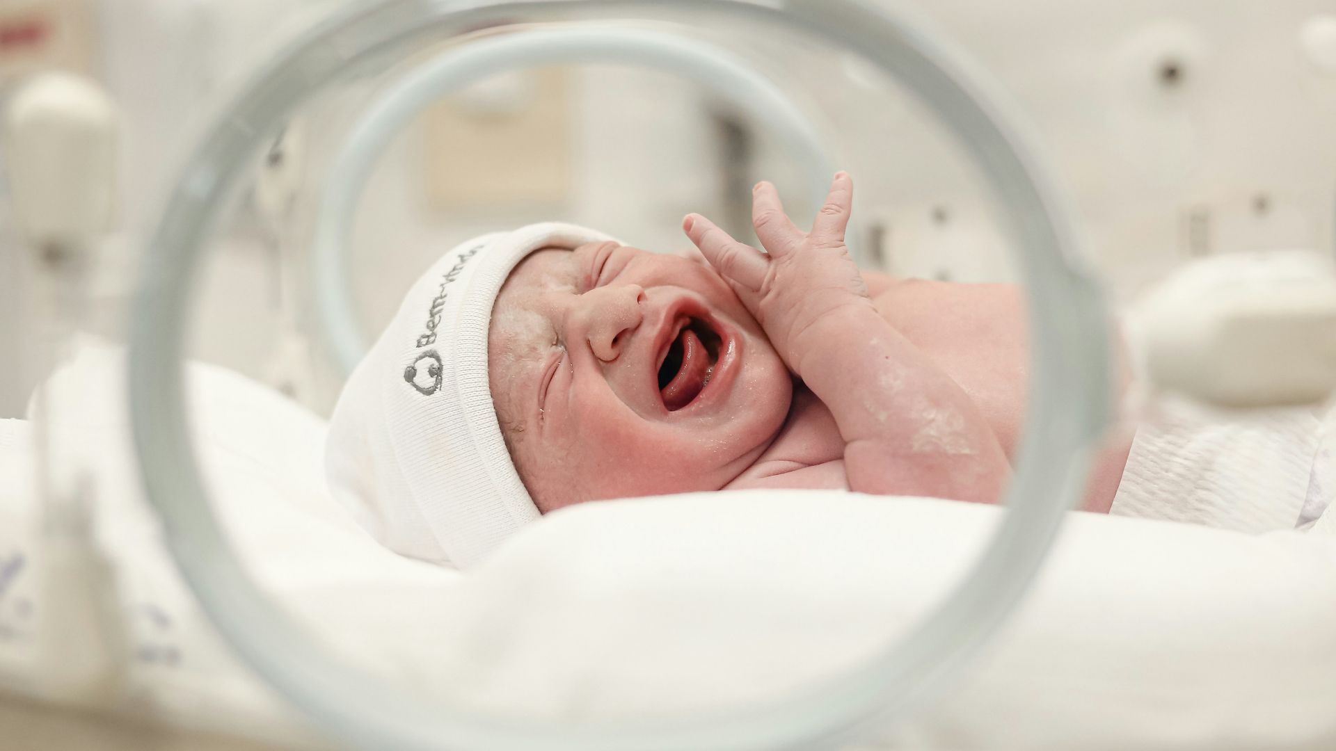 a baby in a hospital bed with its mouth open