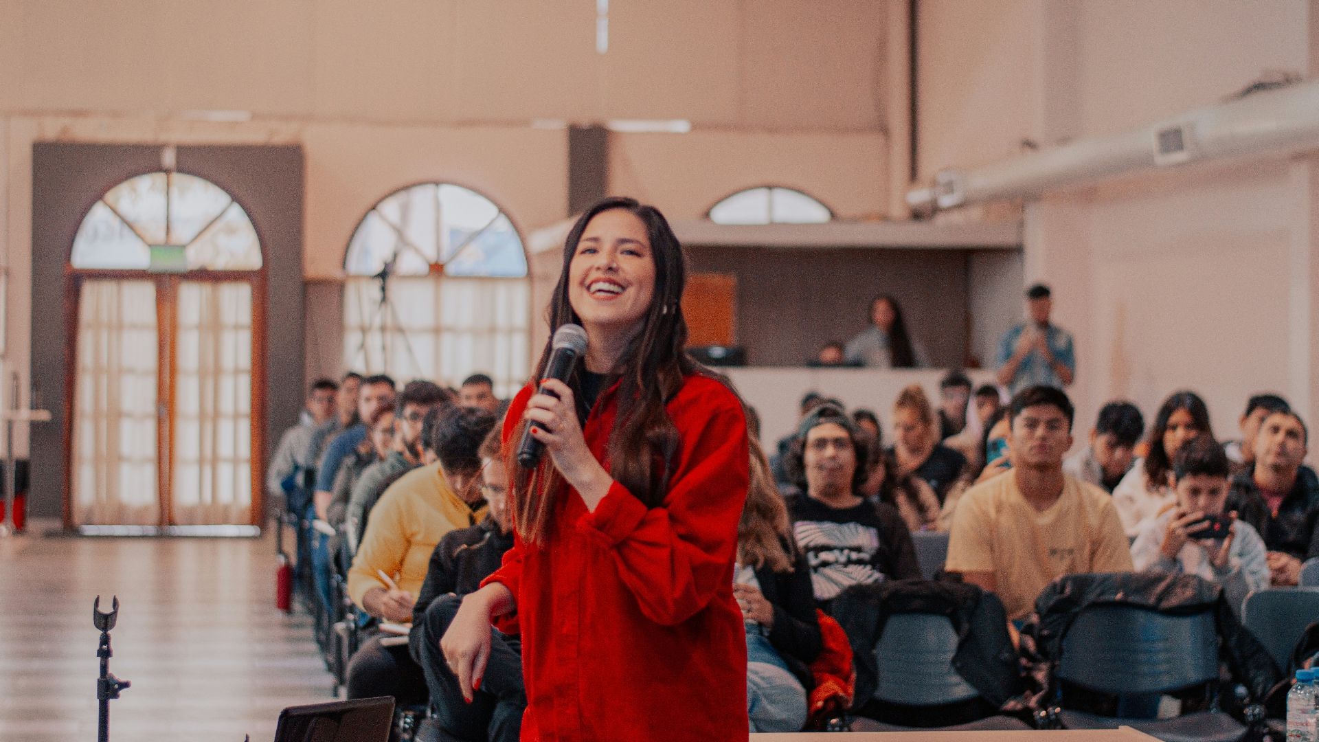 a woman standing in front of a crowd holding a microphone