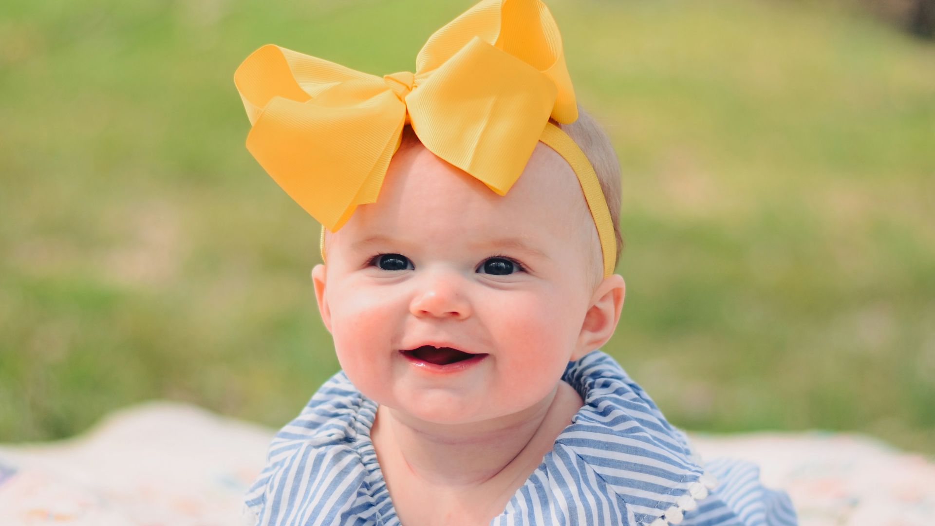 smiling baby lying forward on pink textile