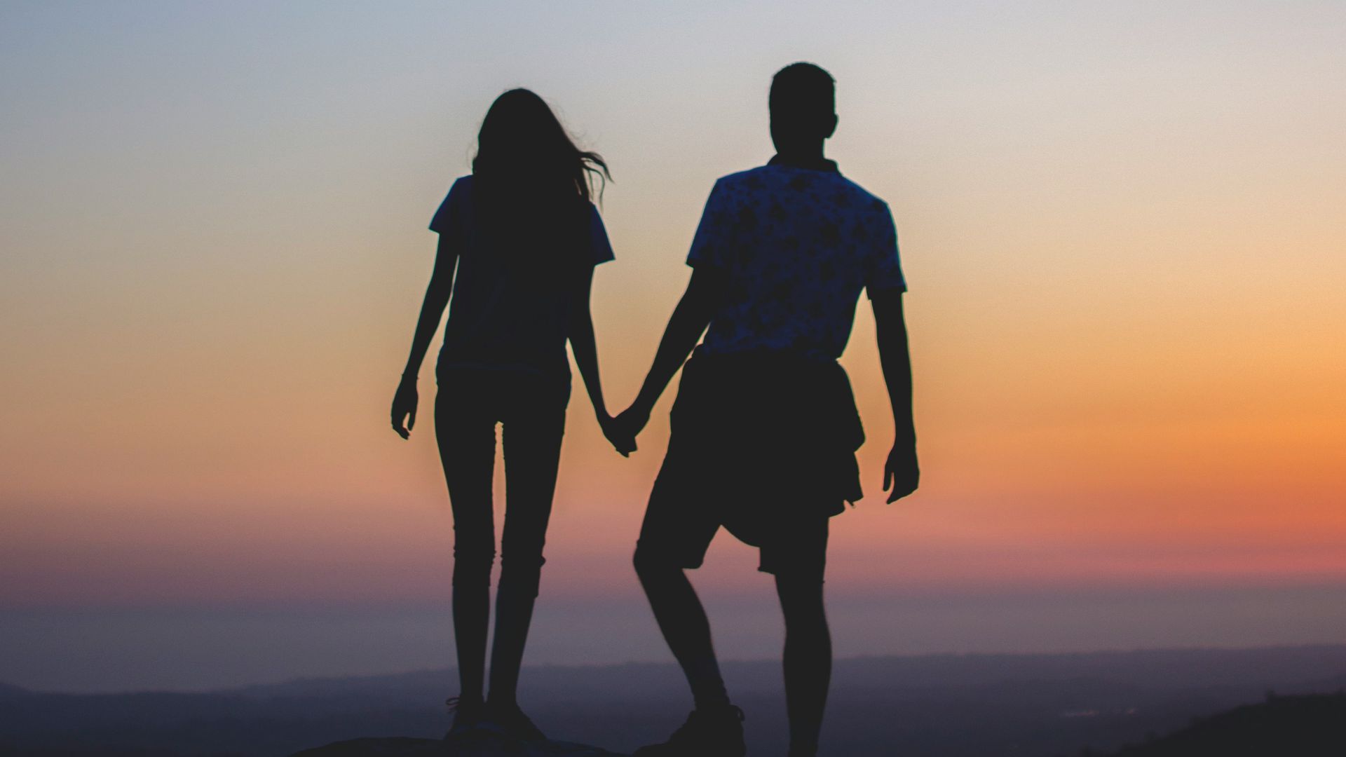 man and woman holding hands in silhouette photography