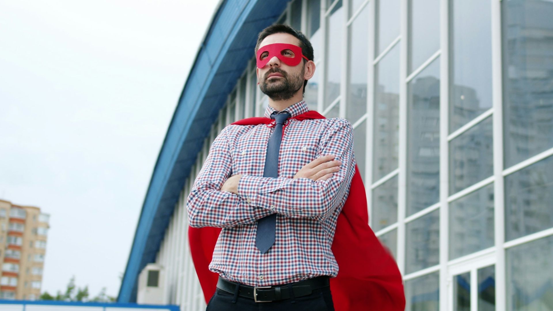 Man in superhero costume standing in front of building.