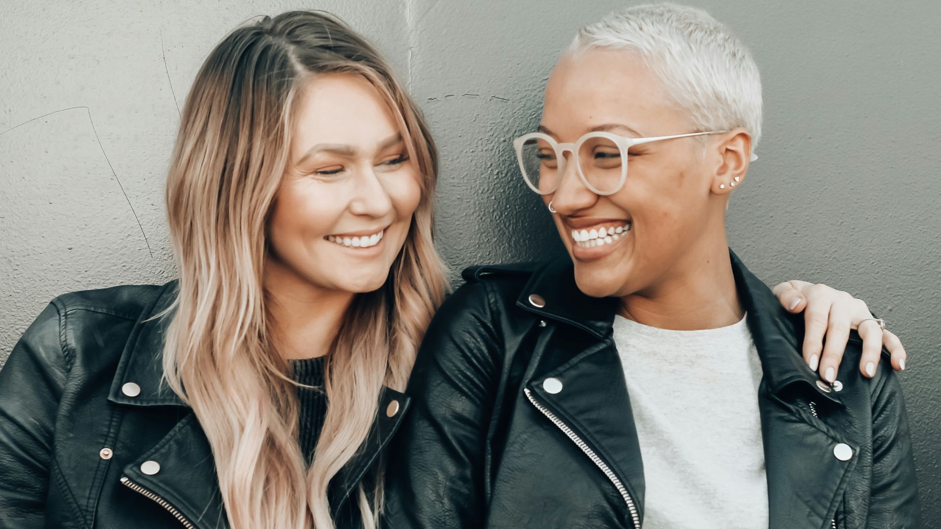 woman in black leather jacket beside woman in gray shirt