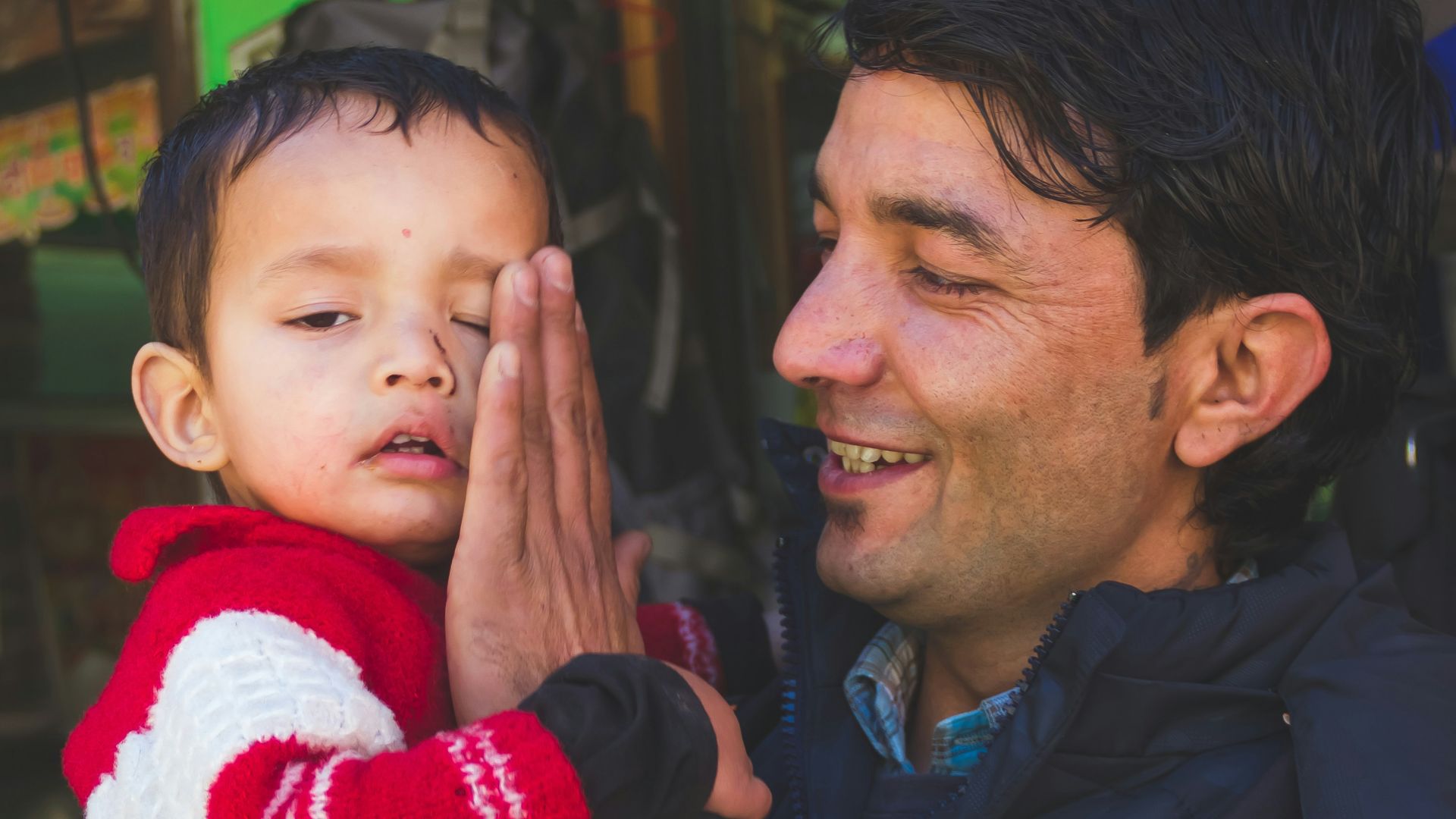 man in black jacket carrying baby in red and white santa man in red and white