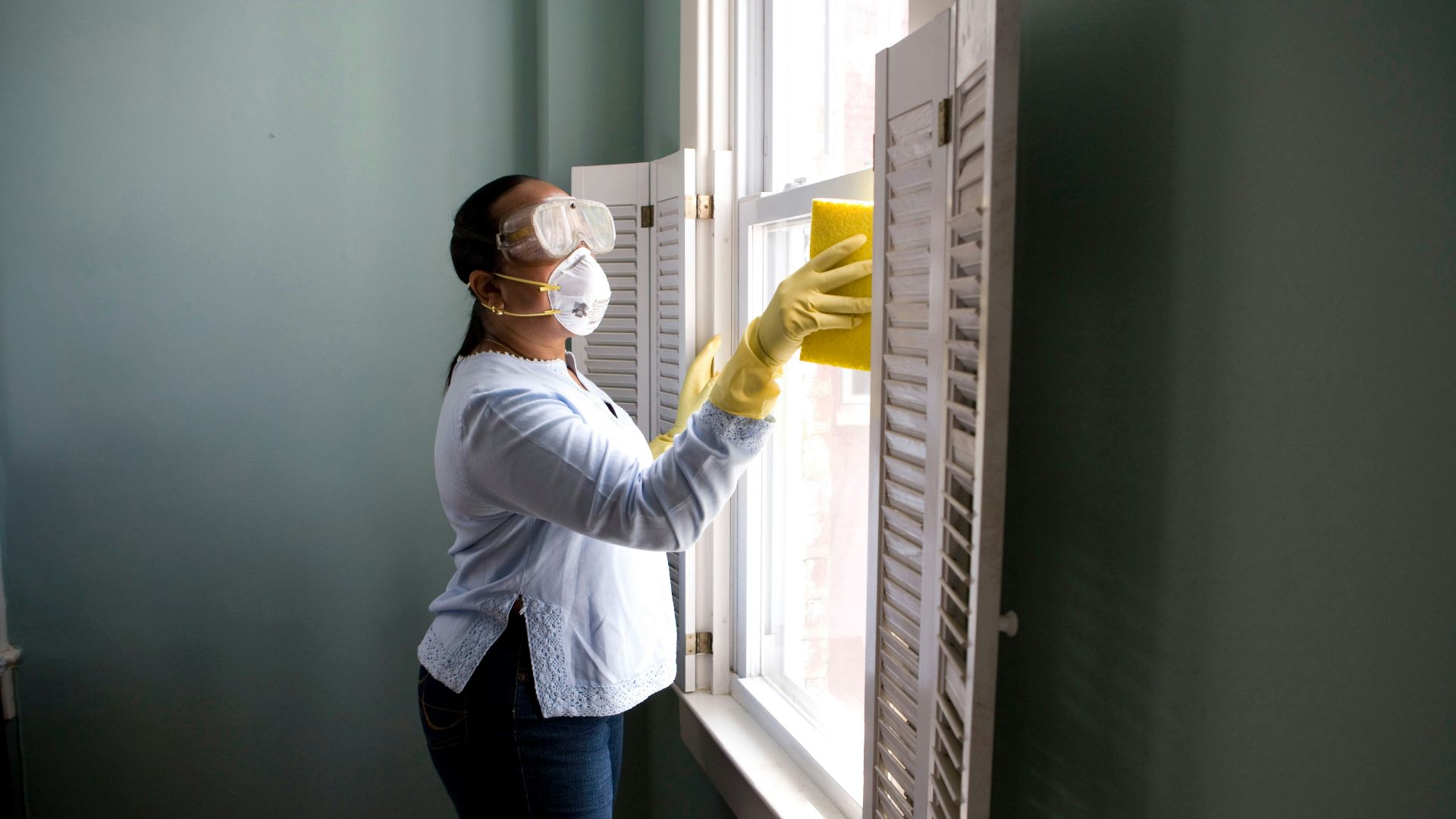 woman in white long sleeve shirt and blue denim jeans standing beside white wooden framed glass