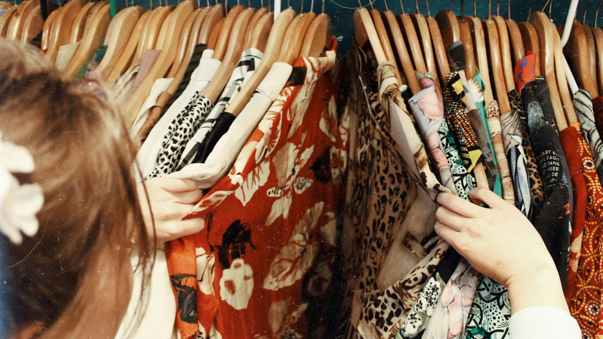 person holding assorted clothes in wooden hanger