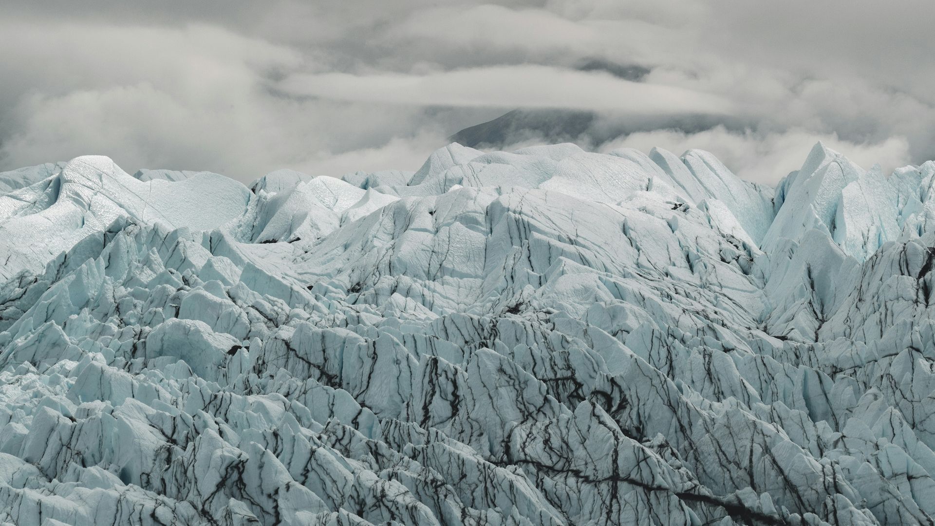 a large glacier with mountains in the background