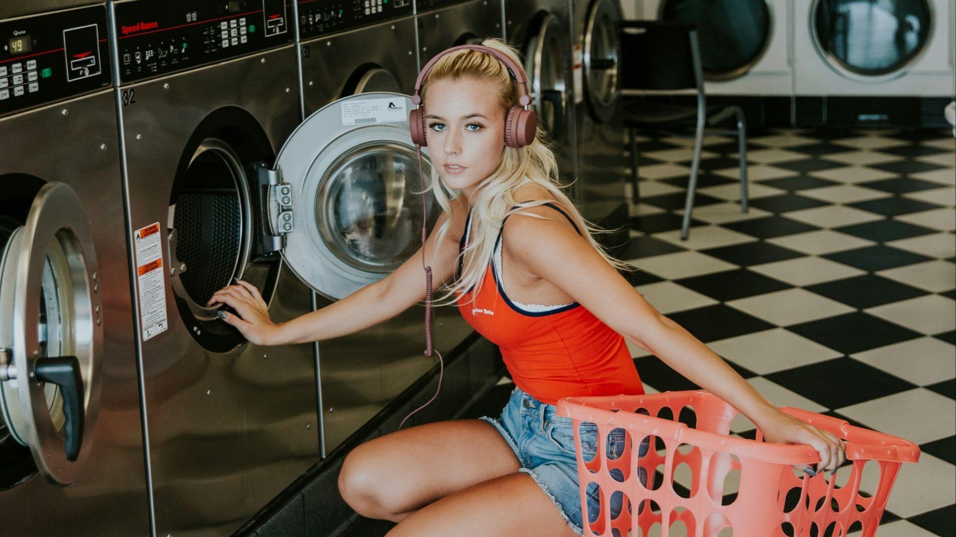 woman kneeling in front of front-load clothes washer inside laundry shop