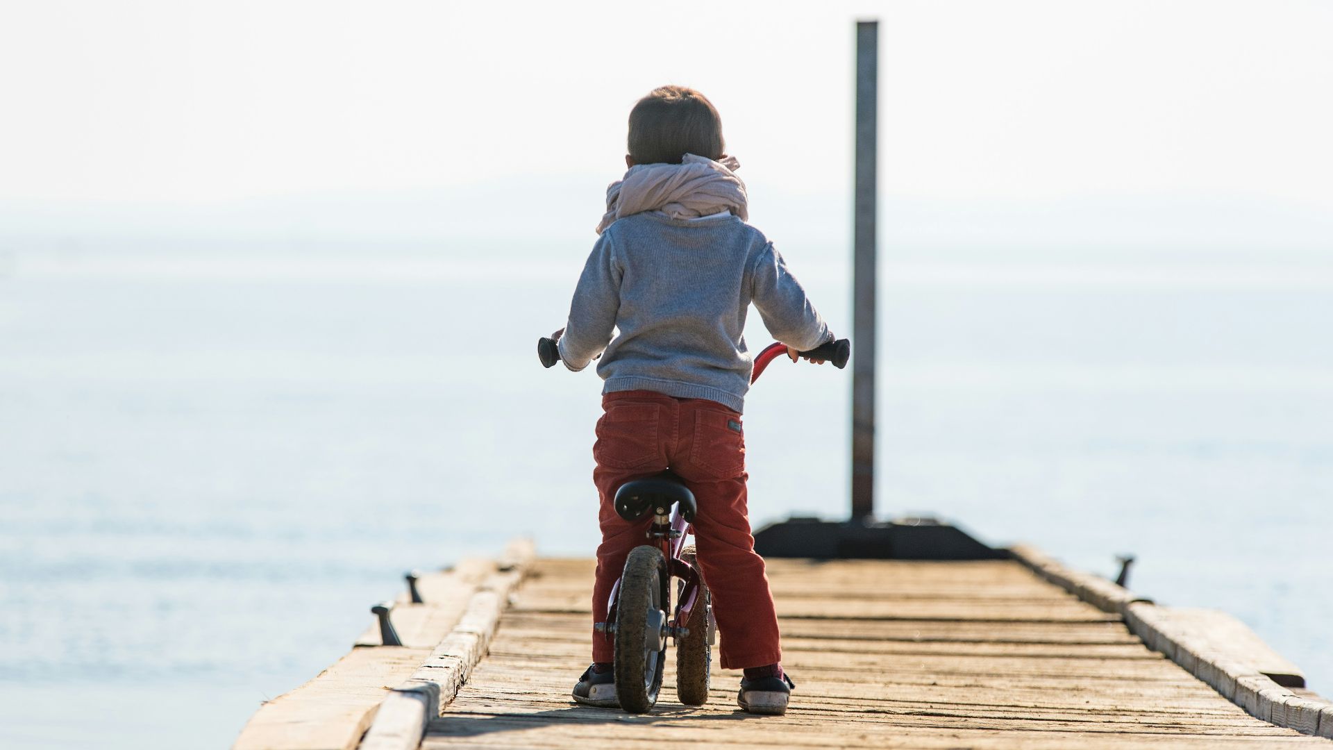 toddler wearing white scarf riding bicycle on brown dockl