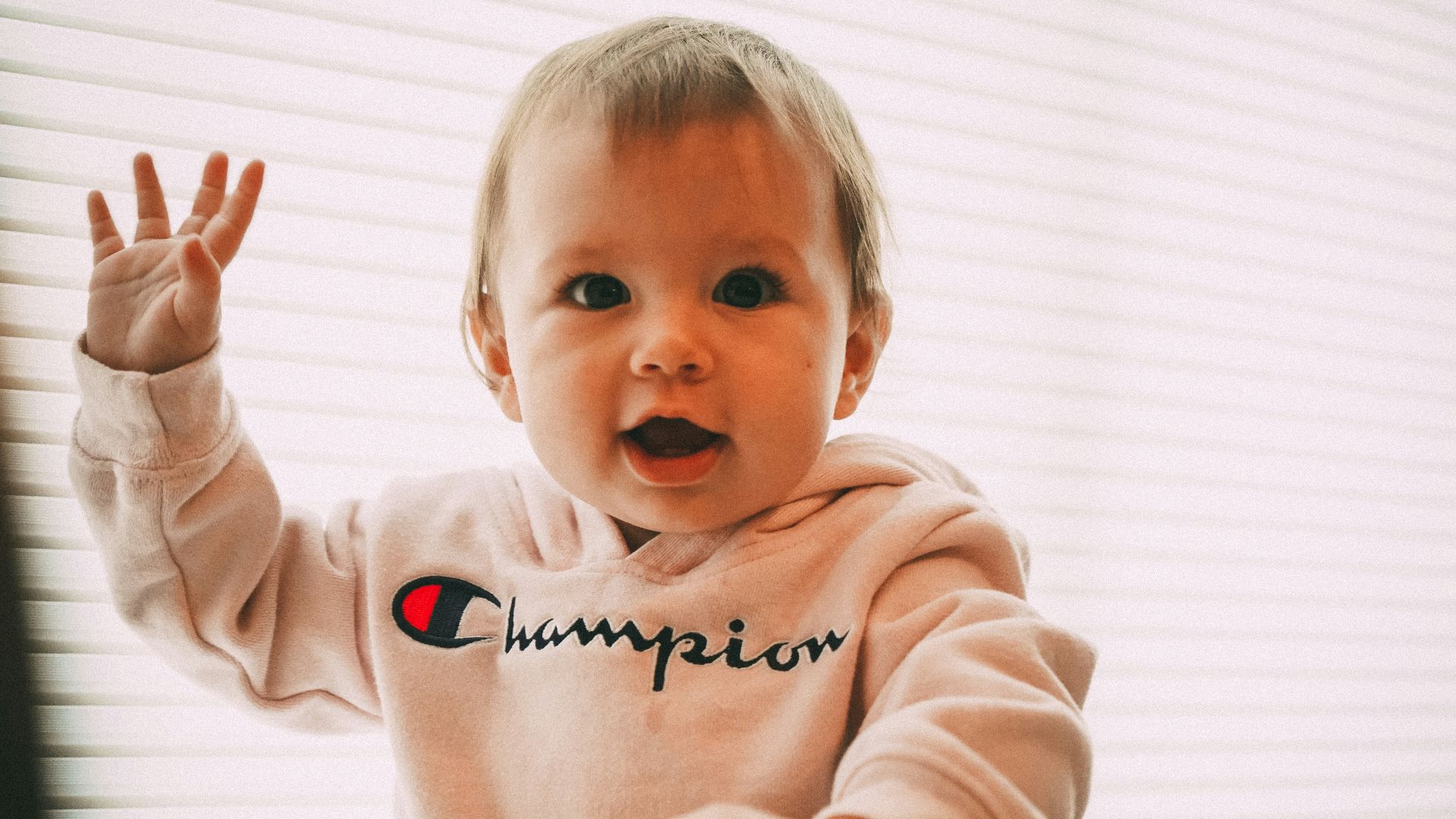 smiling toddler wearing white Champion pullover hoodie
