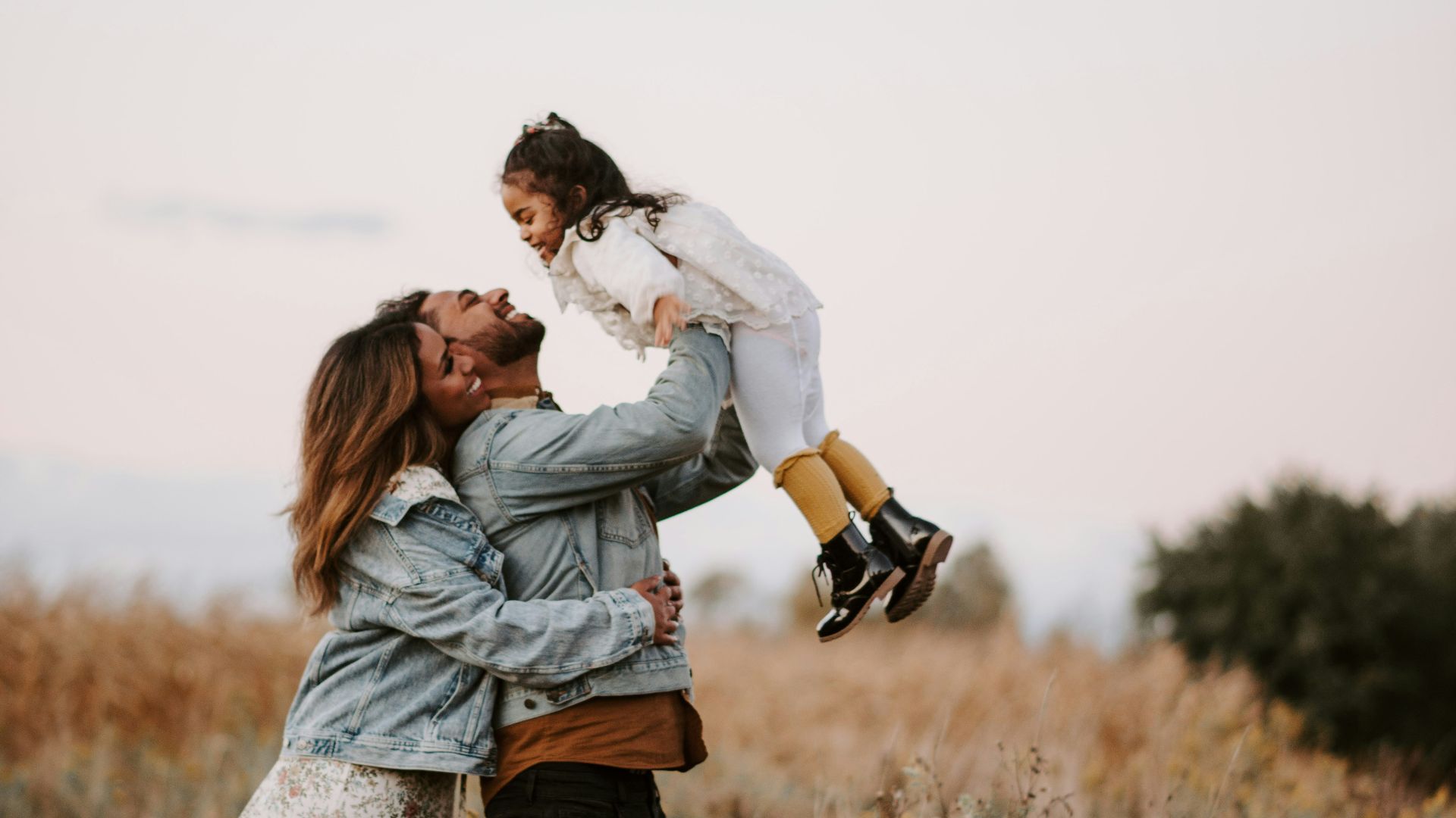 man and woman kissing on brown grass field during daytime