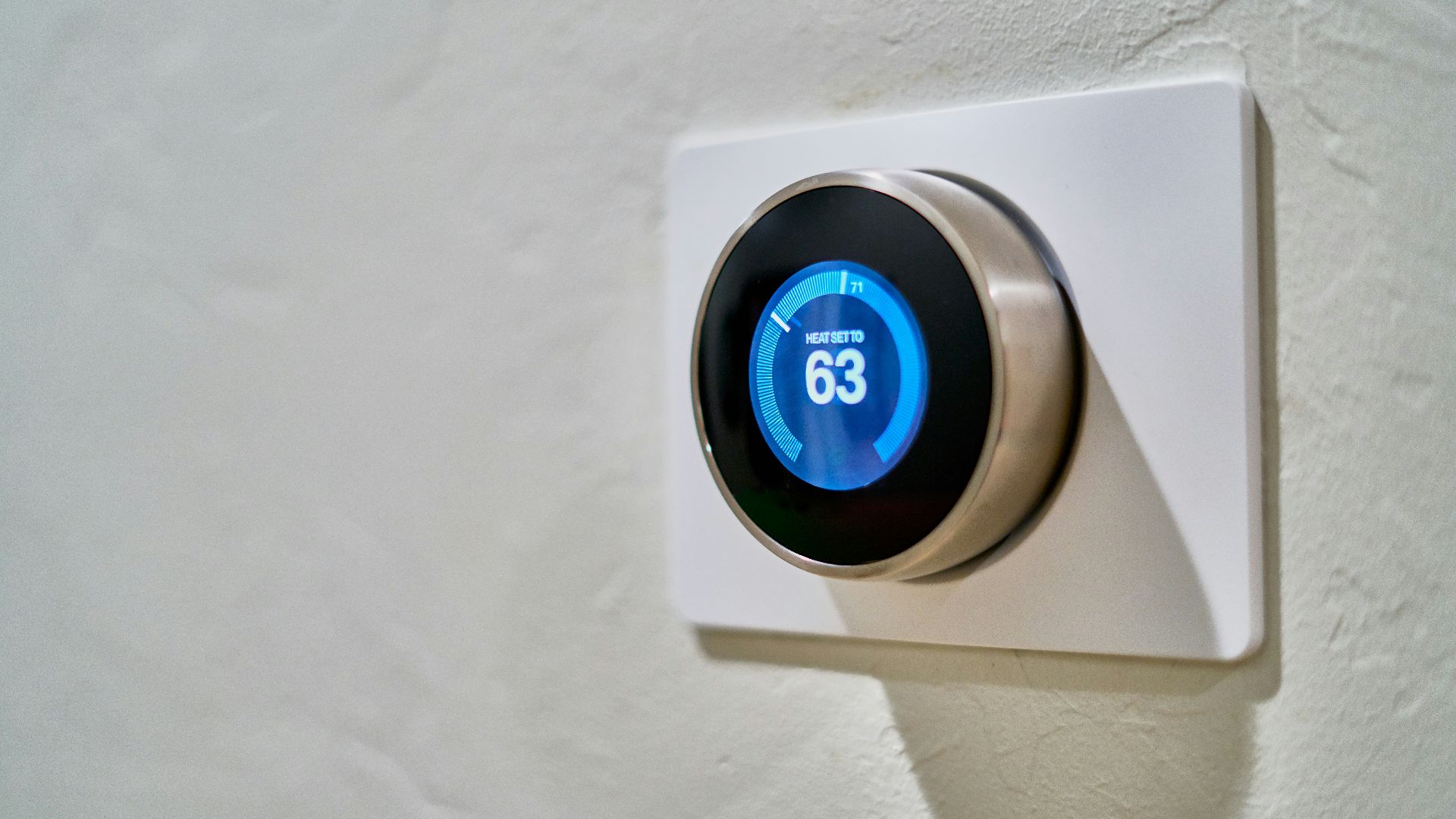 gray Nest thermostat displaying at 63