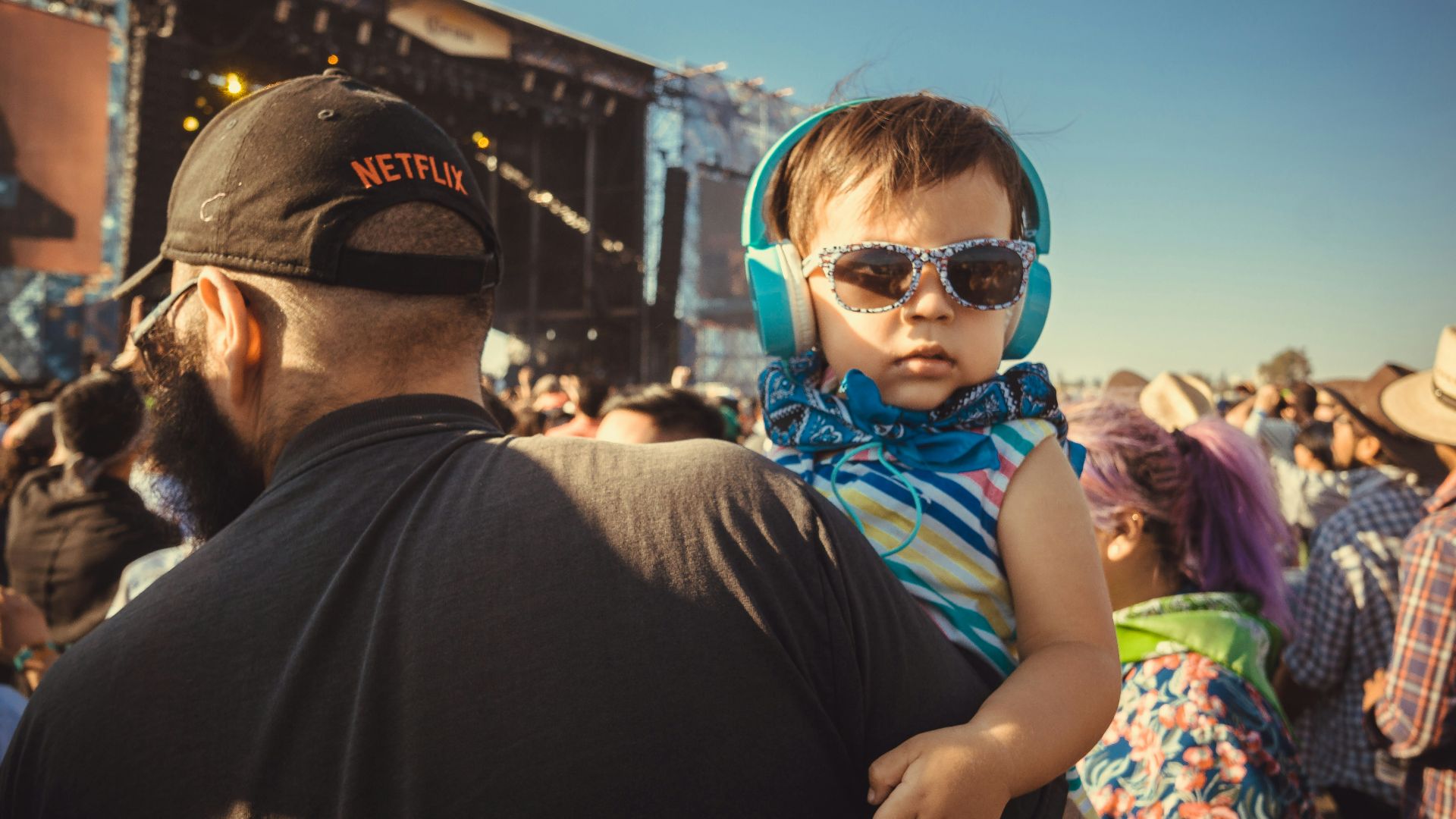 boy carrying a girl wearing sunglasses and headphones