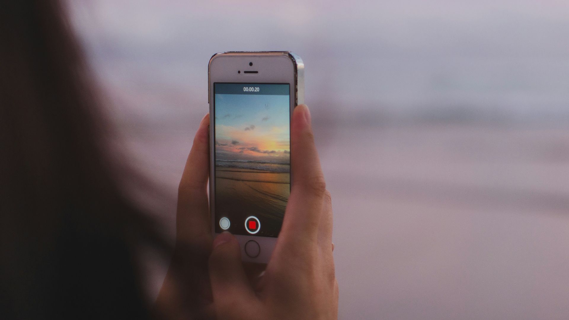 person taking a photo of of open sea and sunset