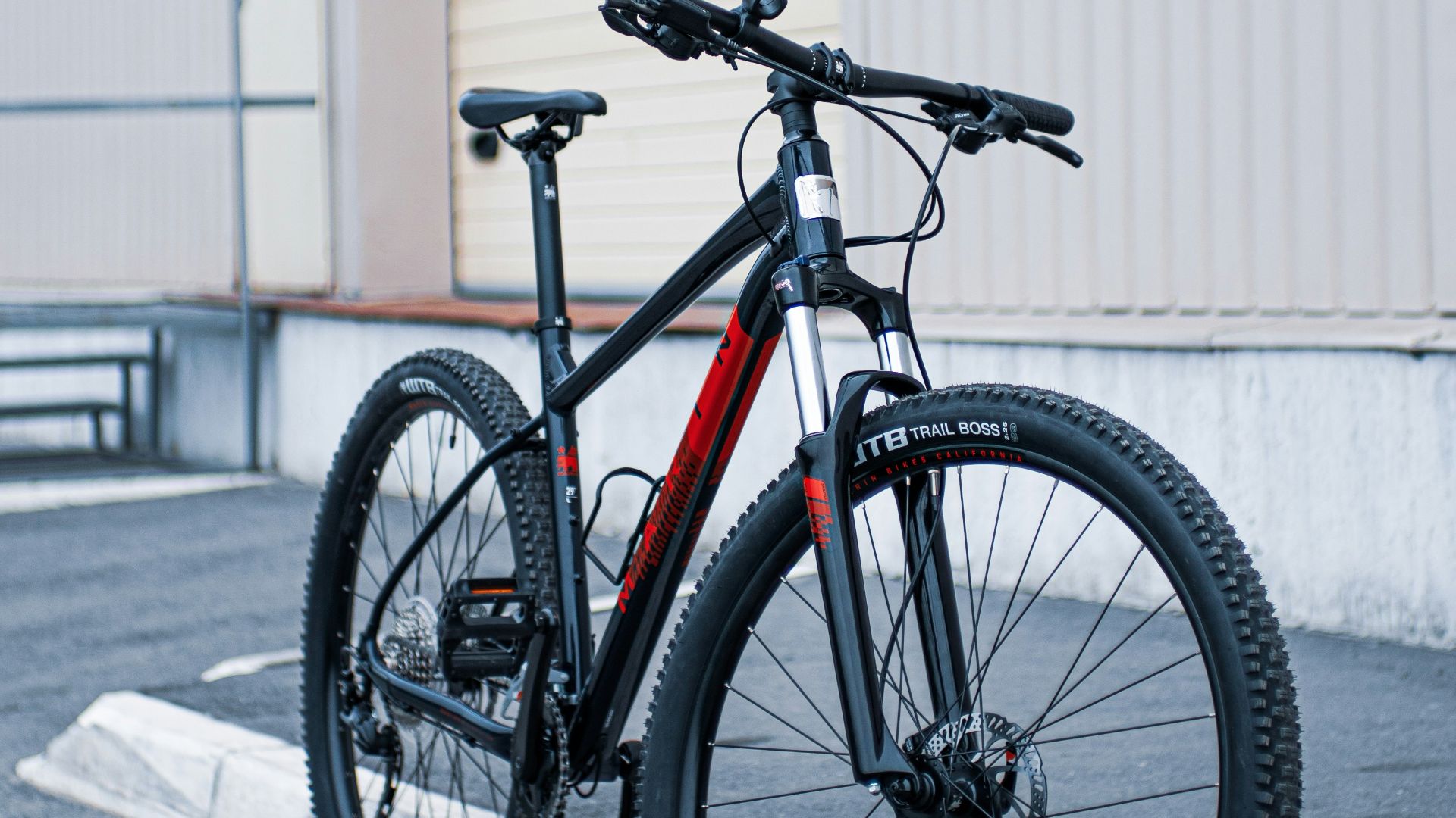 black and orange road bike parked beside white wall