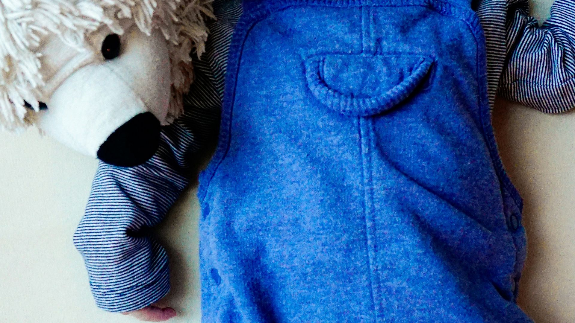 a baby laying on a bed next to a stuffed animal
