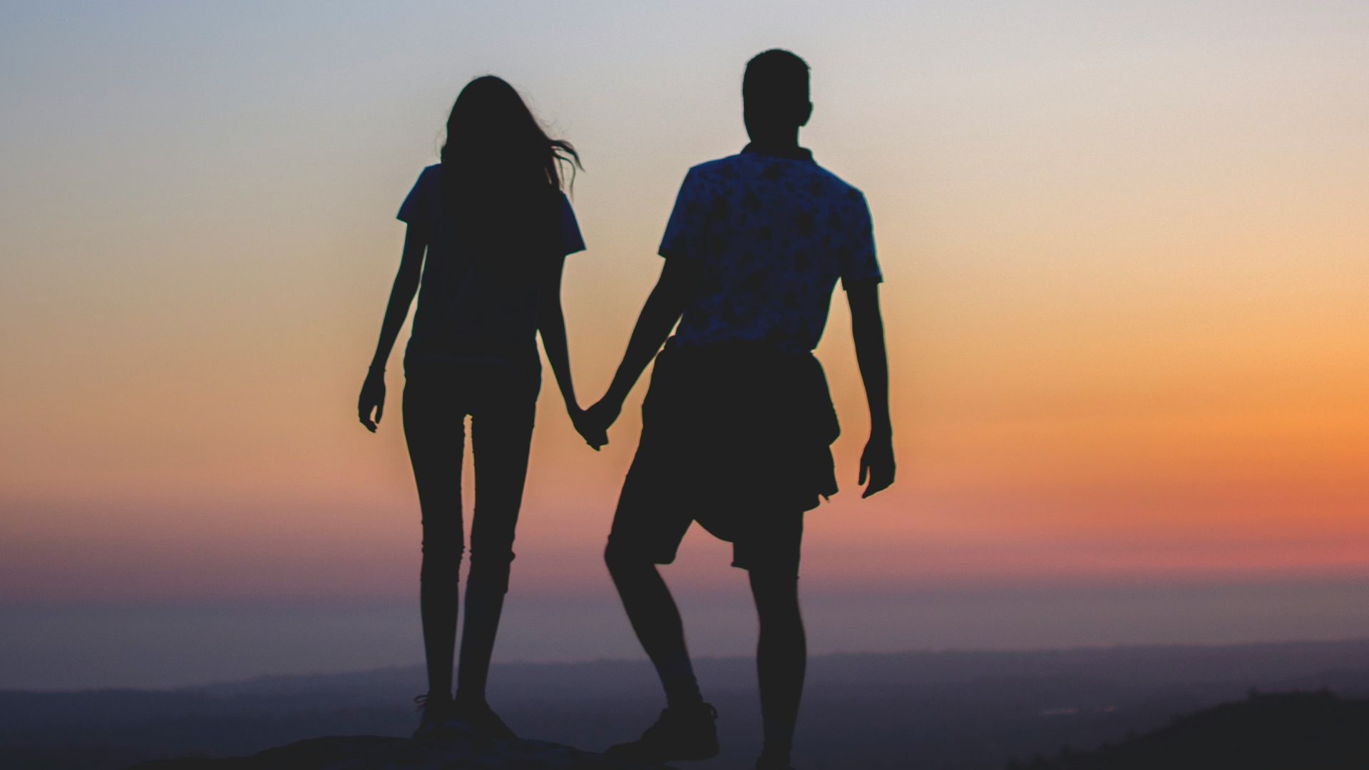 man and woman holding hands in silhouette photography