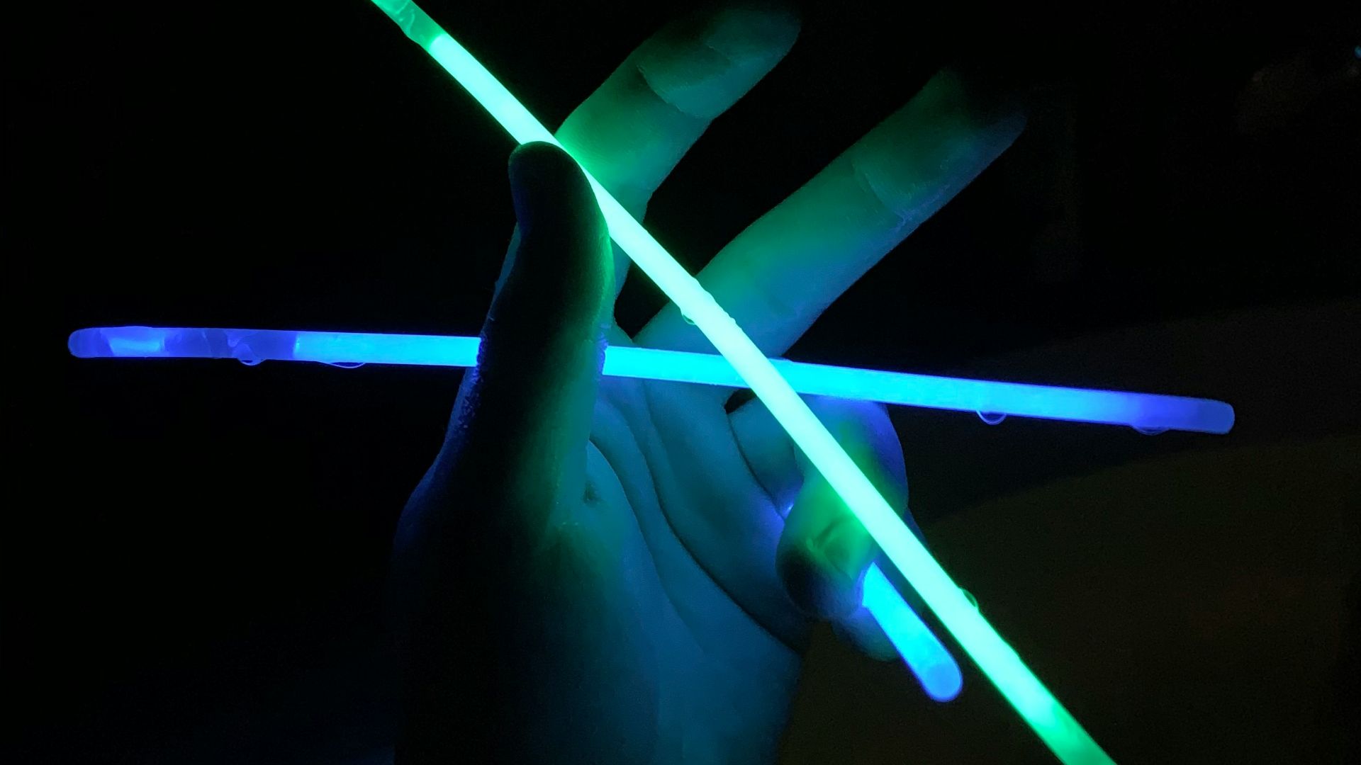 a person holding two glowing sticks in the dark