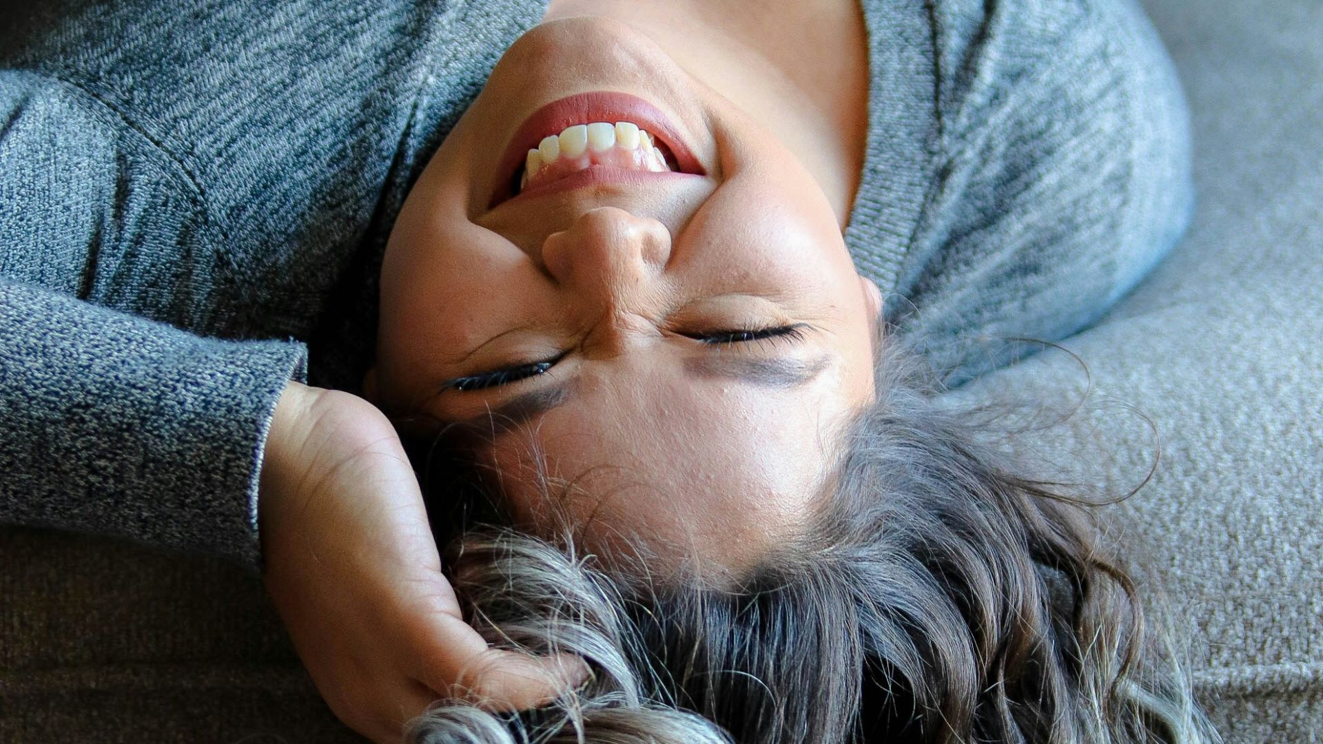 woman laying on couch near throw pillow