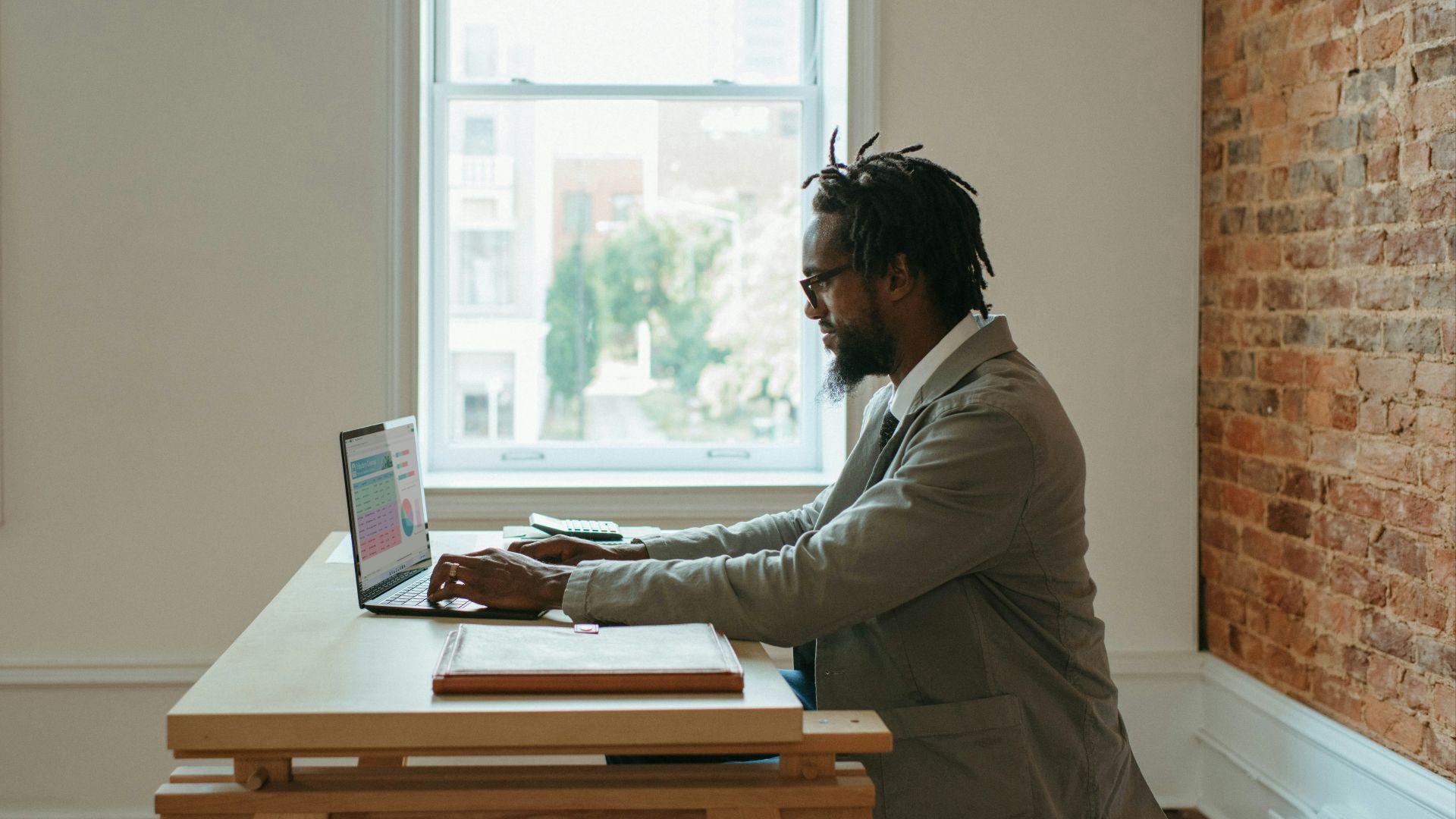 a person sitting at a desk with a laptop and papers