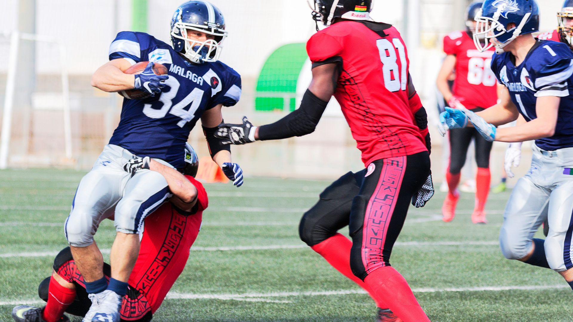 football players in red jersey shirt and red pants running on green grass field during daytime