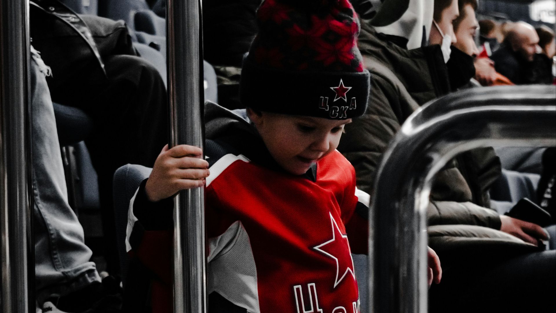 man in red and white jacket and red cap standing beside black car during daytime