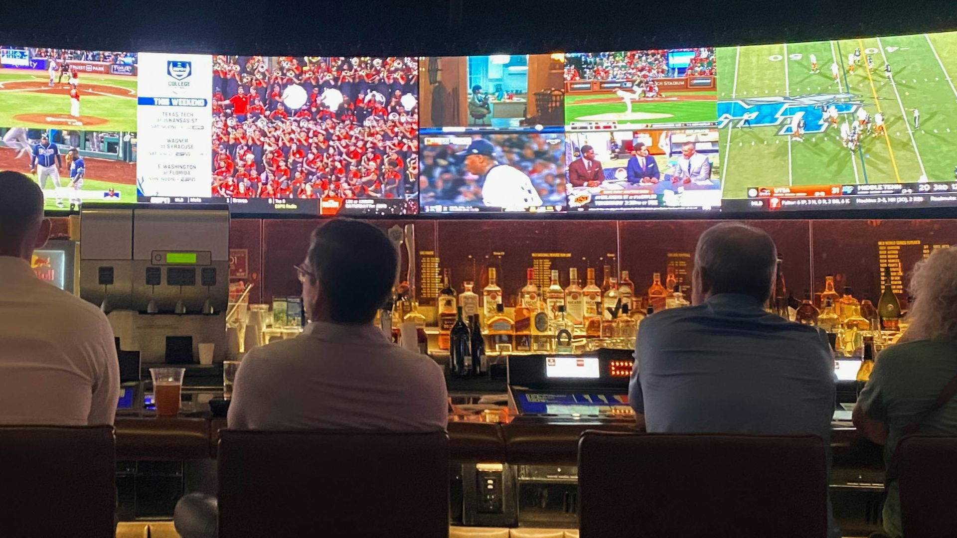 a group of people sitting at a bar watching tv