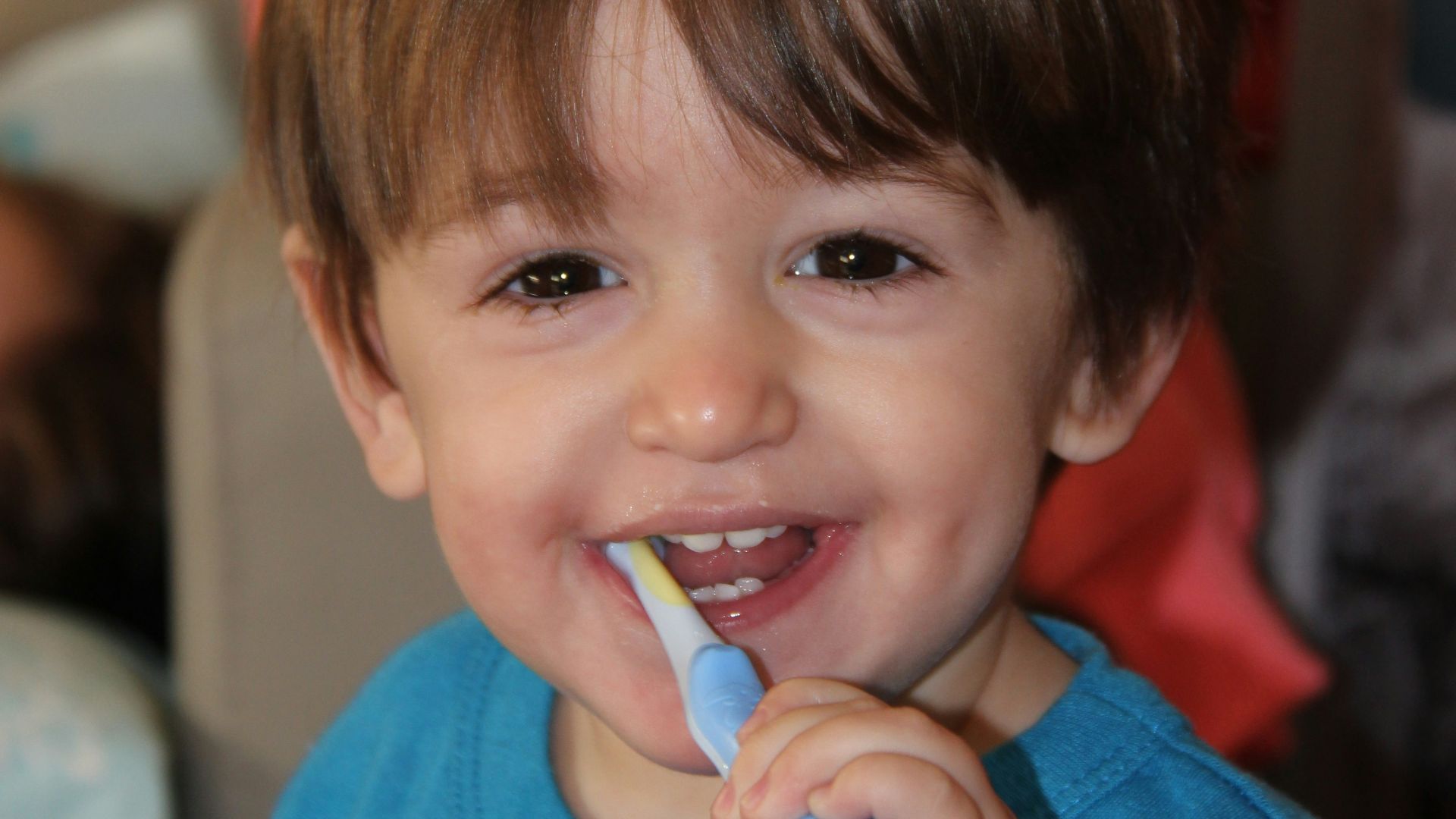 boy in blue crew neck shirt holding blue and white plastic toy